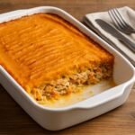 Empadão de frango com puré de batata doce numa travessa de forno, com interior cremoso e dourado